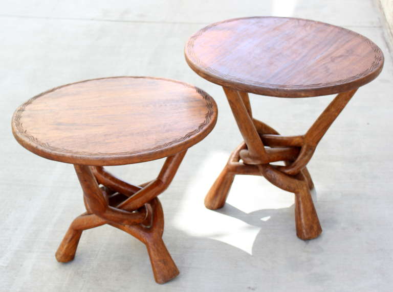 Odd Pair of African Infinity Tables .  The base is carved from a single piece of Wood.   
African hardwood.  Suitable for outdoors 
Smaller table measures 21.25