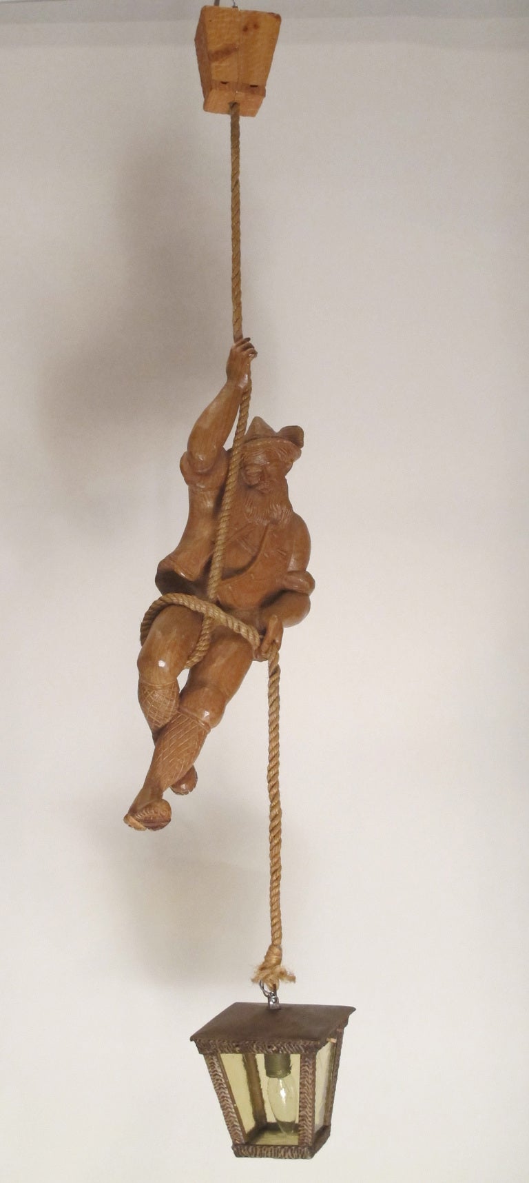 Hand-carved wood pendant light featuring a mountain climber on a rope with a carved wood and glass lantern suspended below him. A very detailed example. Dimensions below are for the figure, overall height is 46-1/2