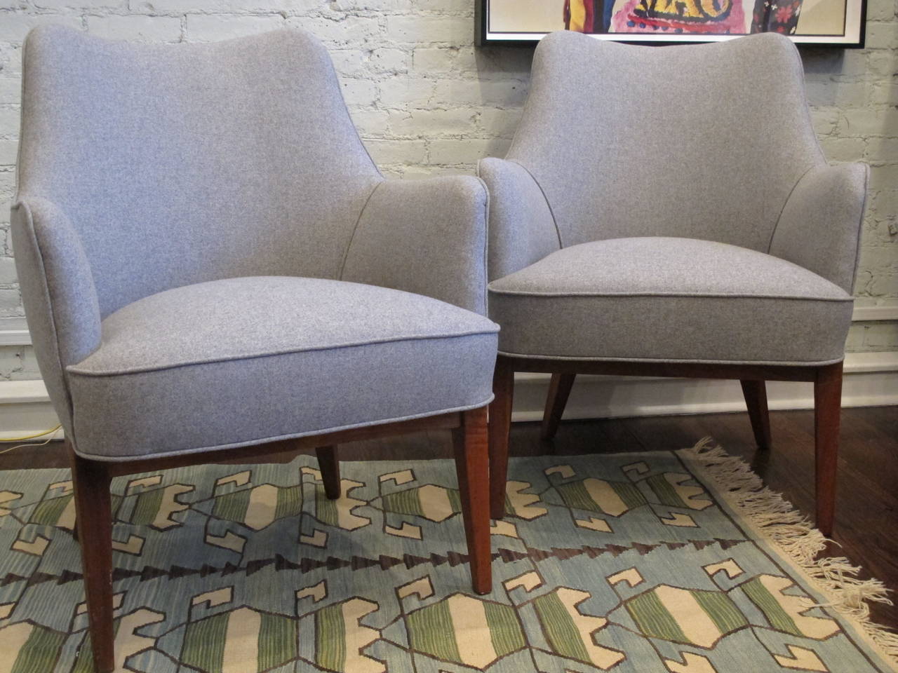 Pair of Danish chairs on teak bases with tapered legs, newly recovered in gray wool flannel. Would work as well as lounge chairs or at a desk. Arm height is 26