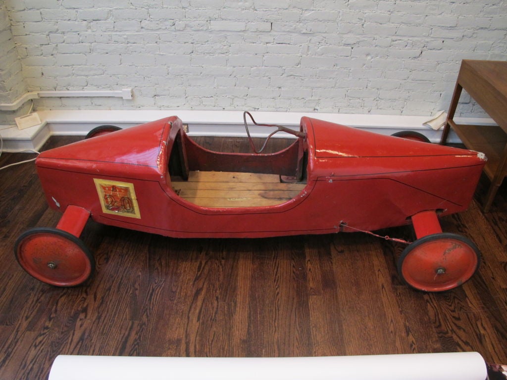 Bright red painted car with black pinstripes. Vintage paper numbers attached to both sides.