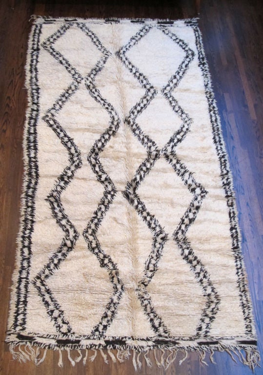 Hand-loomed, Deep pile wool rug with a natural ivory wool field and bold, geometric pattern in warm charcoal, fringed at one end. Others available.