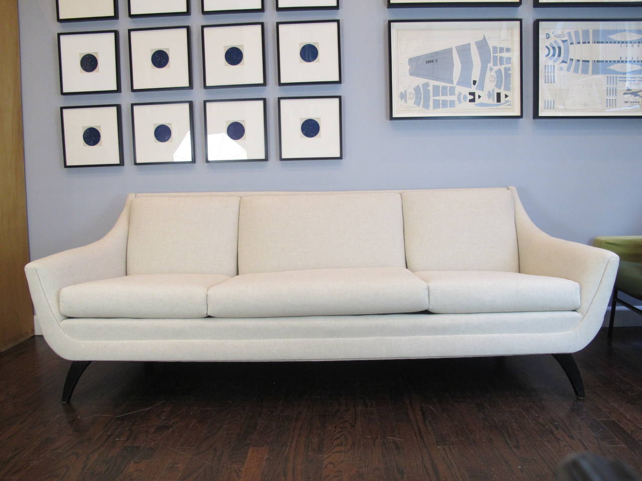 Sofa by Heywood-Wakefield, newly recovered in ivory linen, on black painted maple saber legs. Arms are 21