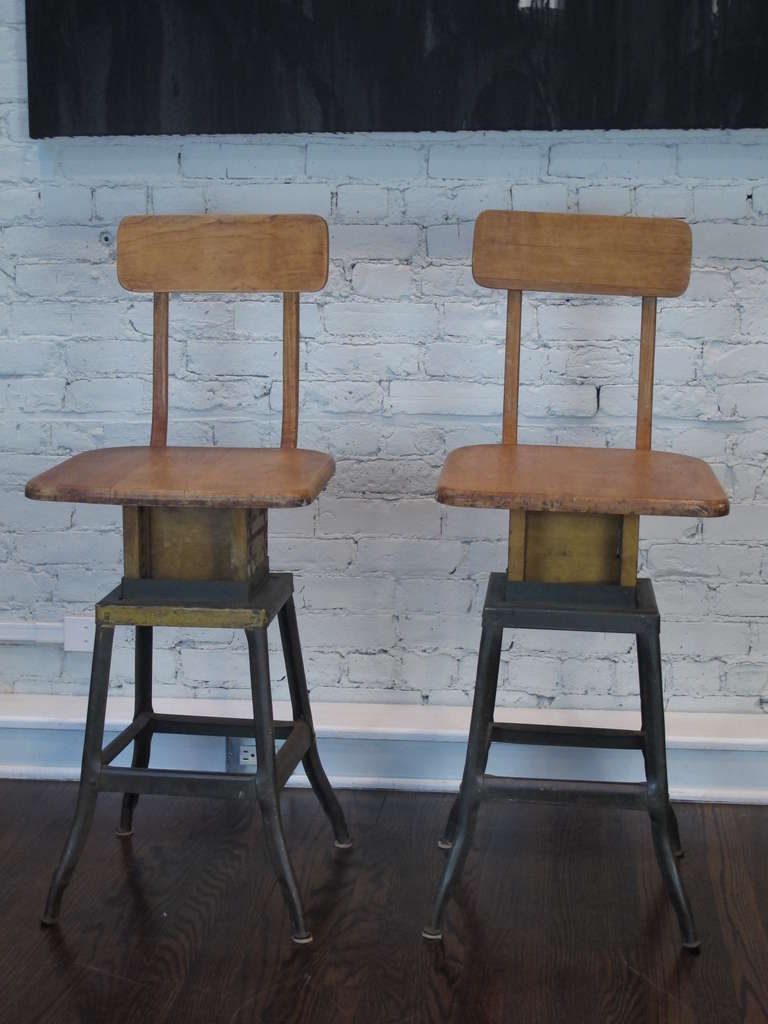 Pair of adjustable stools, with stripped maple seats and backs, on steel bases retaining their original finish and patina. Dimensions below are for the seat height as shown, the seats may be lowered to 20.5