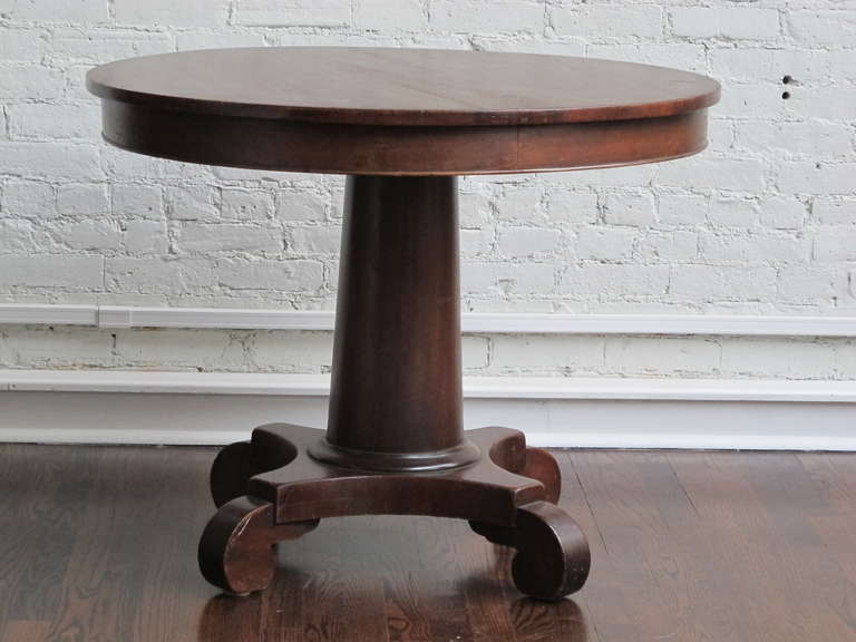 Attractive mahogany center table that could also seat four for dining or cards. Could also be employed bedside or as an end table with high-armed seating. Round top on column base with scrolled feet.