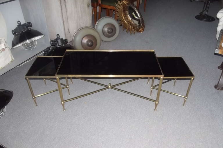 An exceptional three part brass framed coffee table with its original black opaline glass tops attributed to Maison Jansen, Paris.  This table is of the highest quality in perfect condition.  The frame is newly polished.  The dimensions shown below