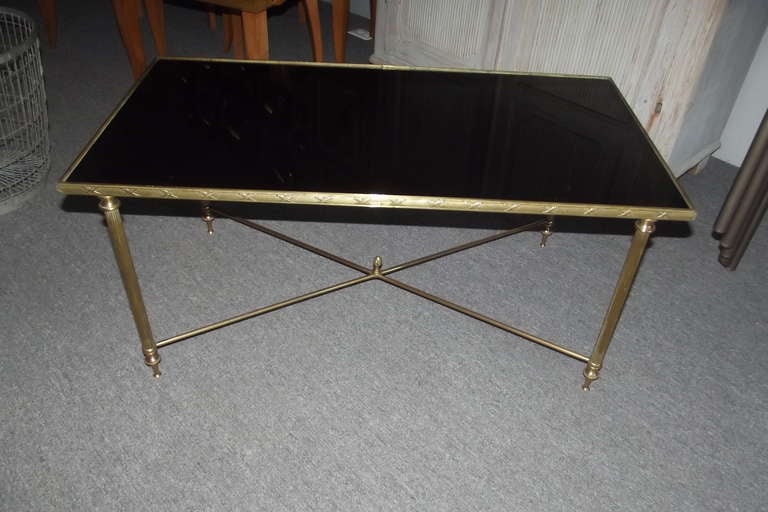 A mid 20th century brass framed coffee table with a black eglomise' top.  The table has a heavy cast edge in the style of Louis XVI and is in excellent overall condition.  It was probably made by Mason Jansen.