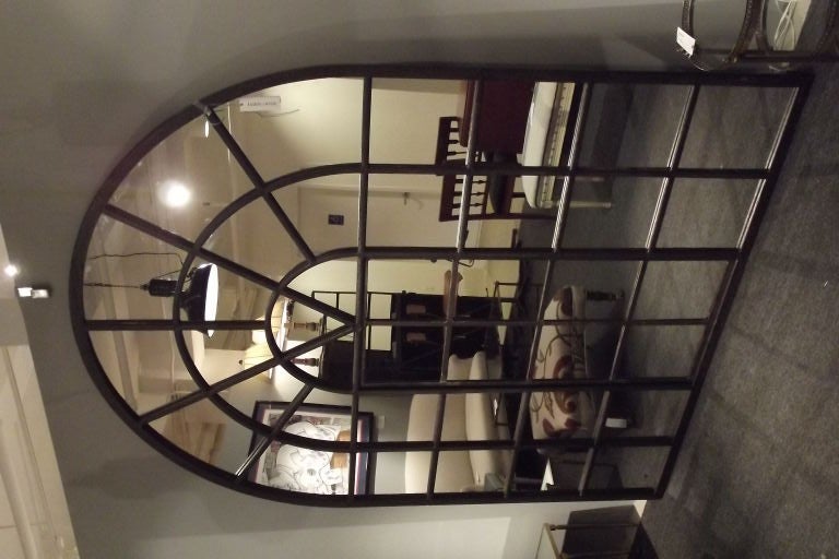 An exceptionally large cast iron Palladian window frame polished and lacquered and fitted with mirror.