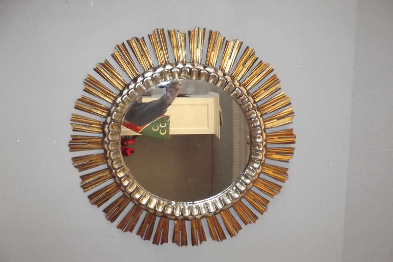 A carved wooden sunburst mirror in gilt and silver gilt with its original looking glass.