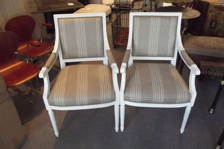 A pair of French armchairs in the Louis XVI style.  The chairs are in excellent condition and newly upholstered in unused vintage linen stripe material.  The seat height is 19