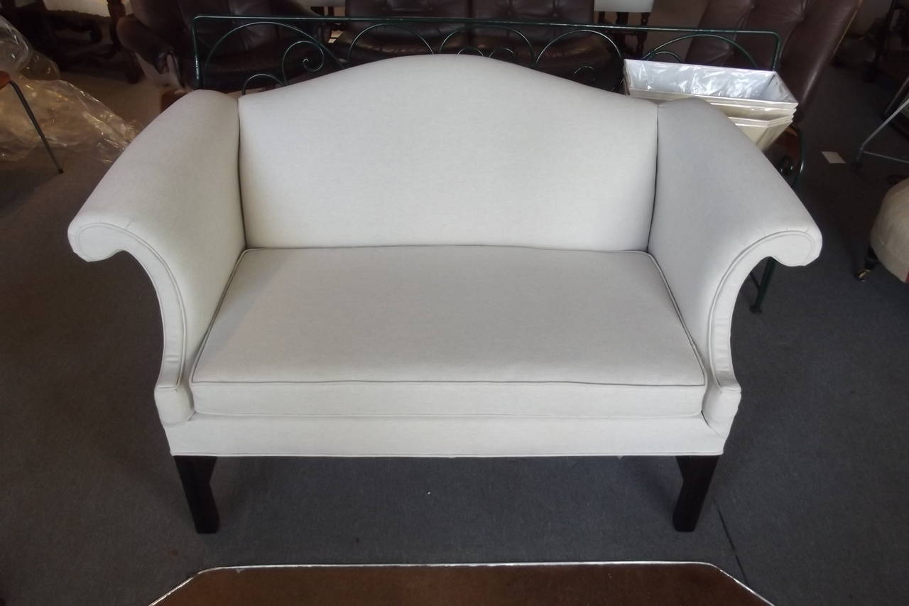 A mid 20th century camel back settee newly upholstered in Boyd's natural linen fabric.