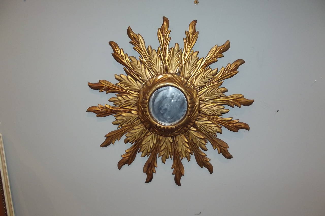 A mid-20th century carved wooden sunburst mirror with its original gilt surface and looking glass.