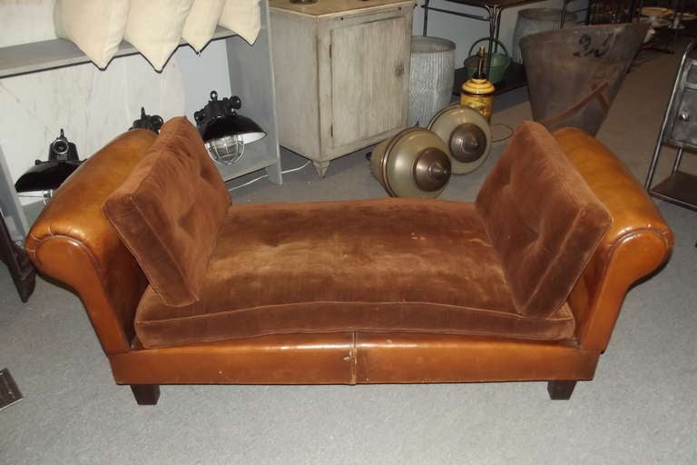 An early 20th century French daybed.  The daybed's leather upholstery is entirely original as are its cushions.  The arms of the daybed adjust to vertical, horizontal and 45 degree positions.  The dimensions below are overall with the arms in the