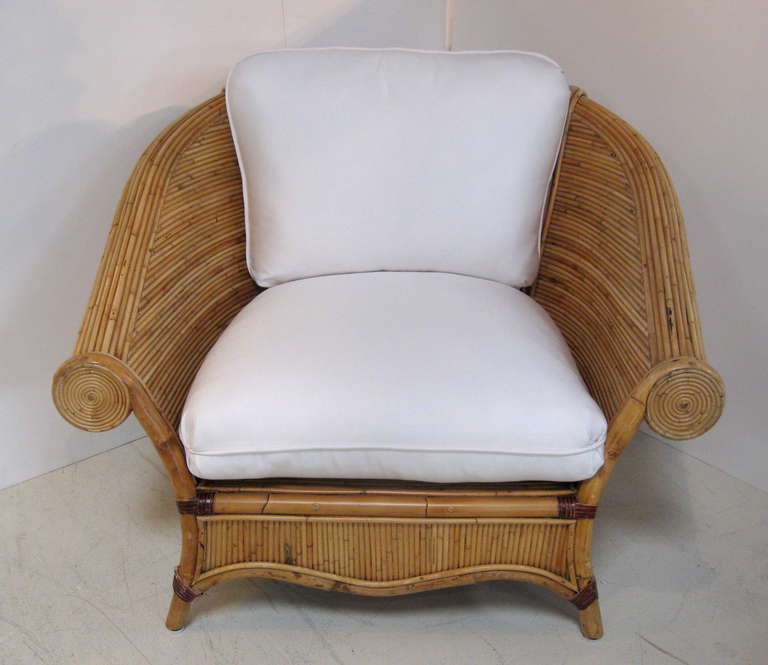 Pair of reeded wood and bamboo chairs with graceful curved backs. Rolled arm design and scalloped bottom complement beautiful form of chair.
New cushions upholstered in white Sunbrella fabric, make chairs very comfortable.