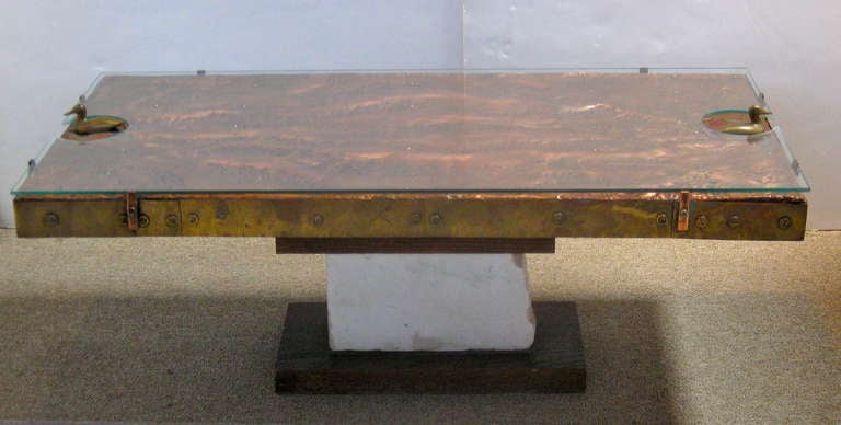 Very unusual coffee table, hand made, featuring a hammered copper top, surrounded by brass trim and a pair of brass ducks at each end.  Base of table consists of wood and white stone. Table top is secured to base by two long pegs that fit into
