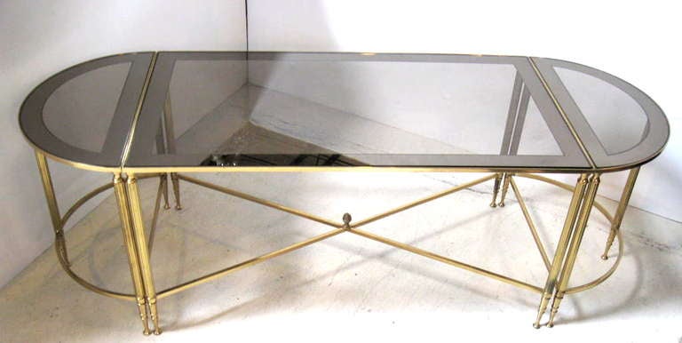 Three part brass coffee table with fitted glass top, in the style of Bagues.  Each section of glass has a mirrored border.  Reeded legs and an acorn finial at bottom stretcher add a look of elegance.  This versitile coffee table consists of a