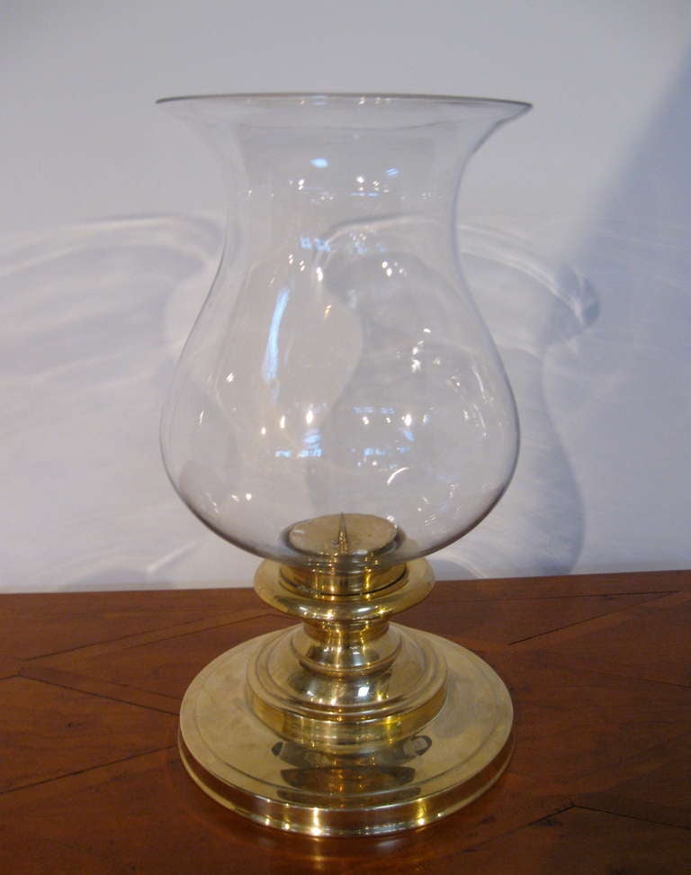 Pair of oversized brass and glass hurricane lamps by Chapman.
Glass is removed by unscrewing inside candleholder.
Glass is clear, as shown in image 3 and 4.