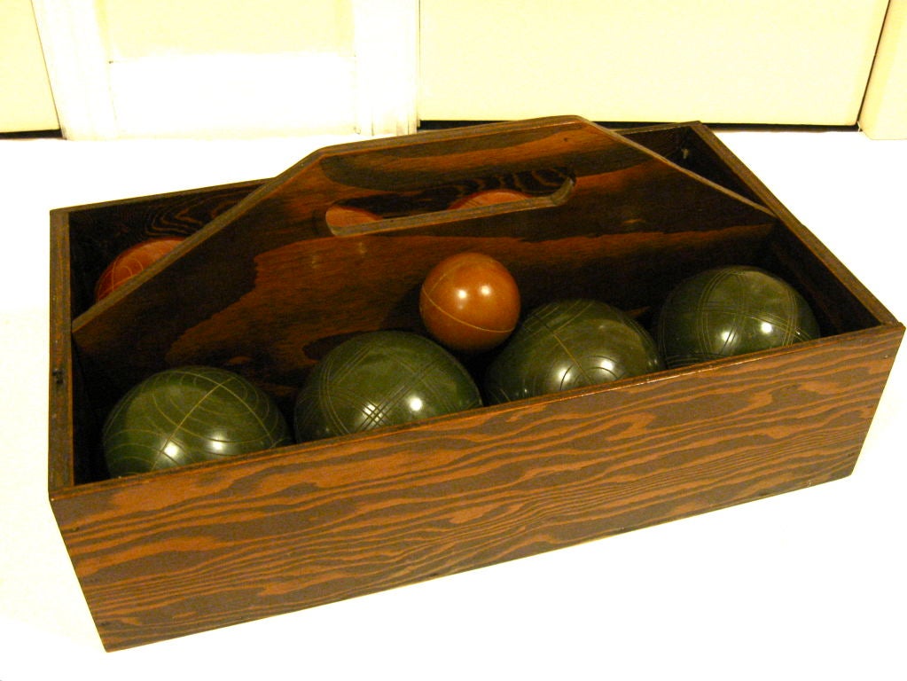 Set of eight vintage bocce balls, plus one target ball, in original wood carrying case.  Balls are green and russet, with an orange target ball.