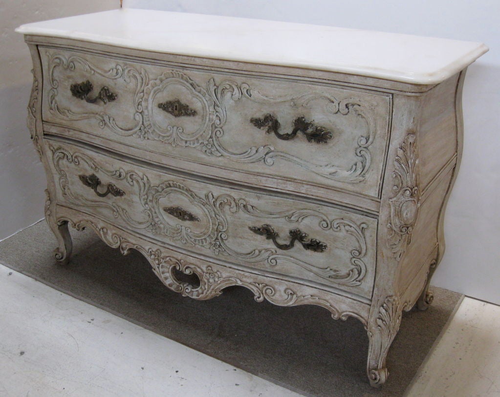Gracefully curved commode / chest in the style of Louis XV, with a painted finish and marble top. Interesting applied details with antiqued metal handles and escutcheons complete the look.