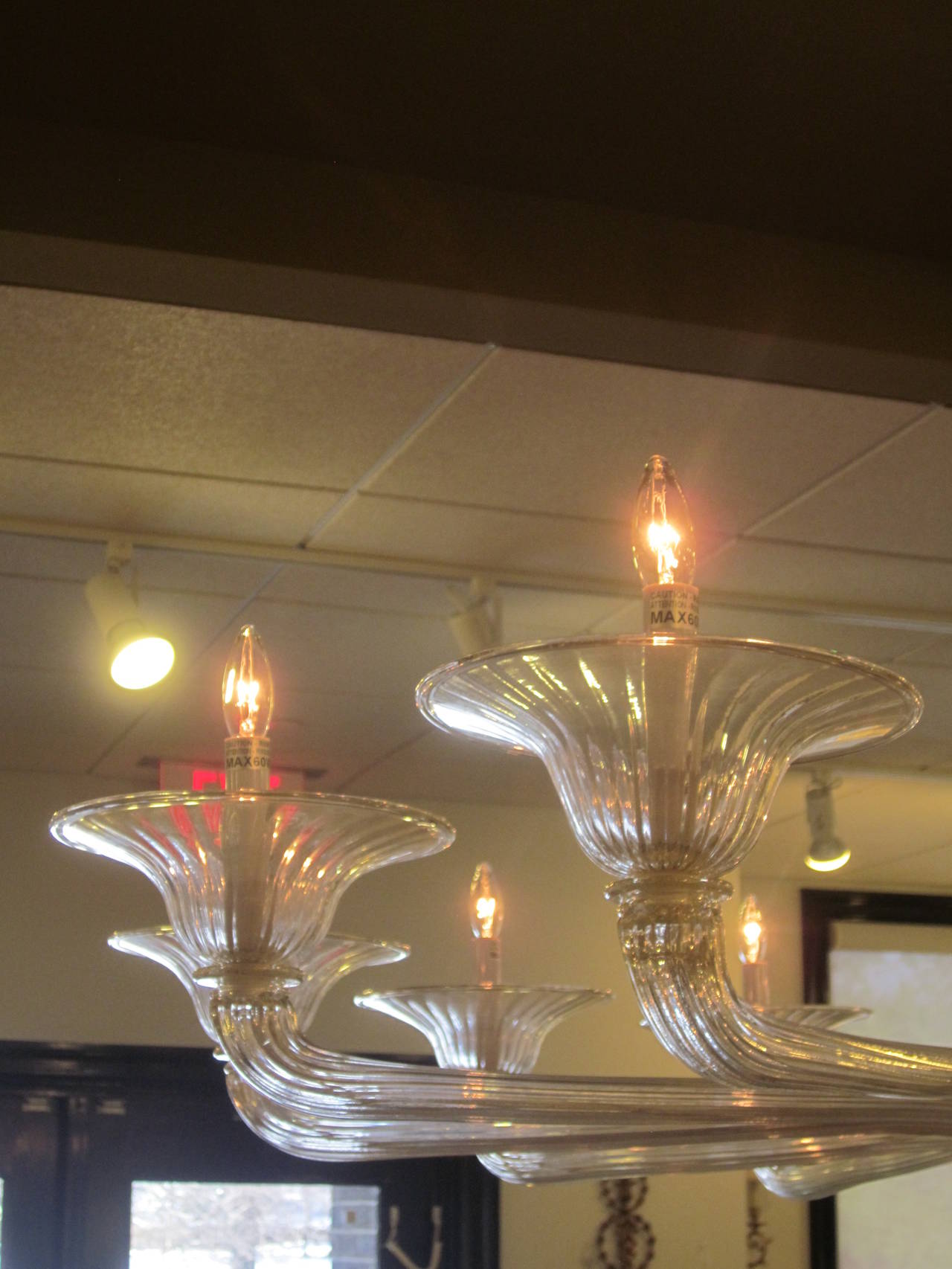 Elegant, very large handblown Mid-Century Modern style Venetian glass chandelier and pendant with twelve arms arranged in a sober pattern around a central bowl. The handblown glass is clear interspersed with flecks of gold leaf. 

The height is