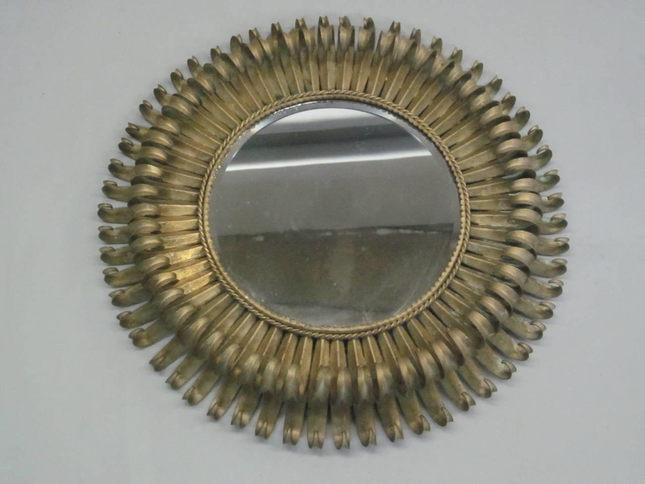 Elegant, stunning French Mid-Century mirror with a double level of sunburst rays that add depth and drama to the piece. The modern neoclassical frame of the mirror is in gilt iron.