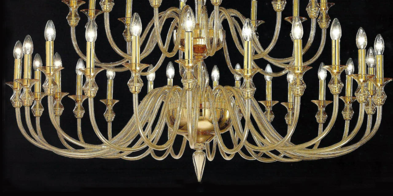 Two large, sober and elegant double tier Venetian glass chandeliers in clear amber glass with 24 lower arms and 12 upper arms and set up for 36 candelabra lights at up to 60 watts each. A pure, modern neoclassical statement. The height of the