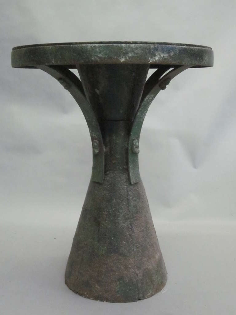Elegant, sculptural French Early Modern gueridon, side table, center table, pedestal or console in hand-hammered wrought iron with a bronze patina. The top is attached to the cylindrical expanding base via four supports, each fastened and decorated