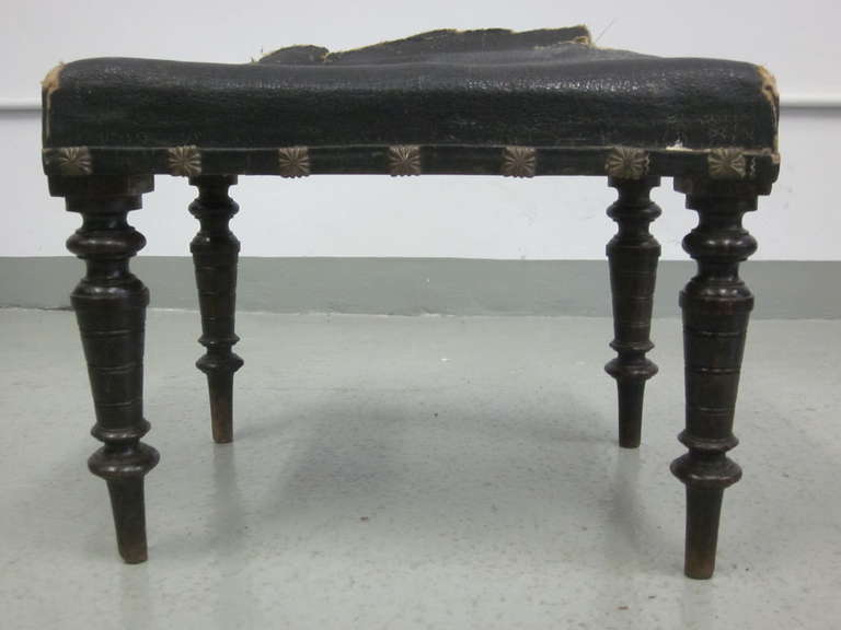 Elegant Pair of Italian Mid-Century Modern Neoclassical benches, ottomans or footstools with hand-carved and turned legs supporting a studded leather top. 

Leather needs replacement.