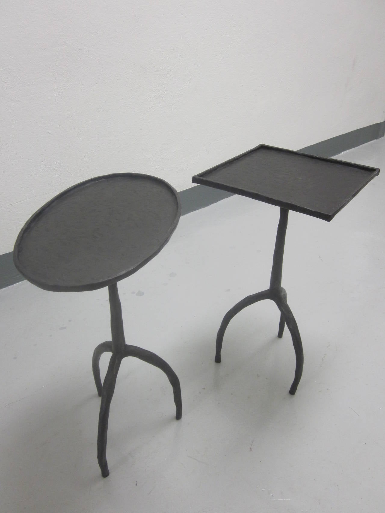 Exquisite and exotic pair of French hand-hammered iron side tables or gueridons or end tables reflecting both Modern and Brutalist sensibilities. Sold by the pair only. 

One with square top, the second with an oval top. The table with square top