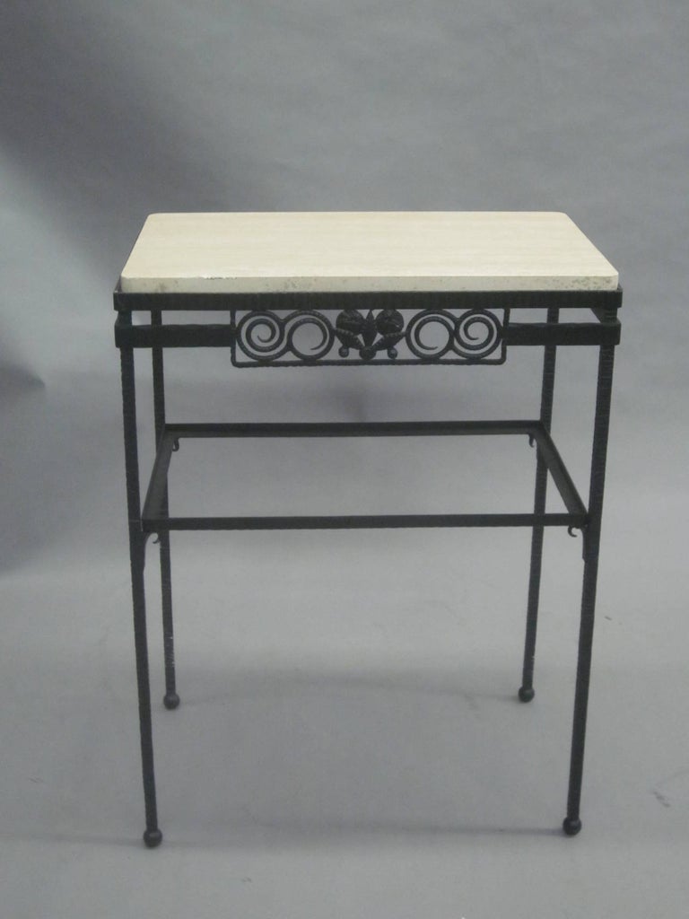 An elegant double tier French midcentury / Art Deco console, side table or nightstand composed of hand-hammered wrought iron with a top of travertine and lower level of glass. The wrought iron front panel having a modern neoclassical motif of leaves