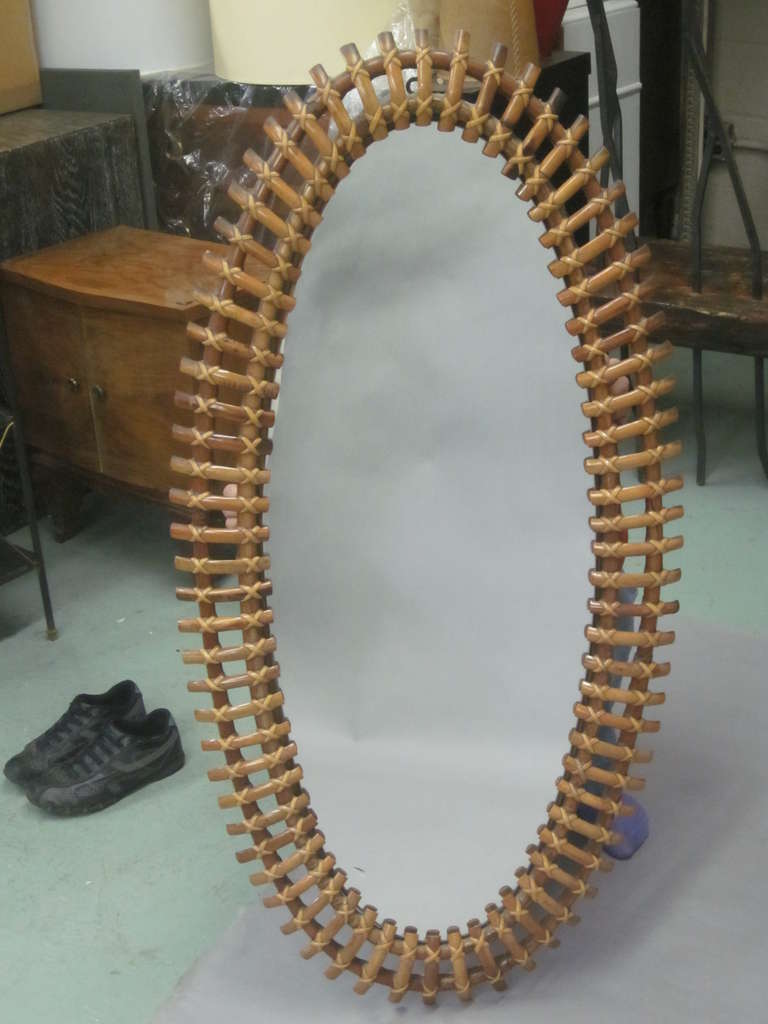 Italian Mid-Century Modern mirror attributed to Franco Albini with an oval frame in rattan with the spokes radiating outward in the form of a sunburst.