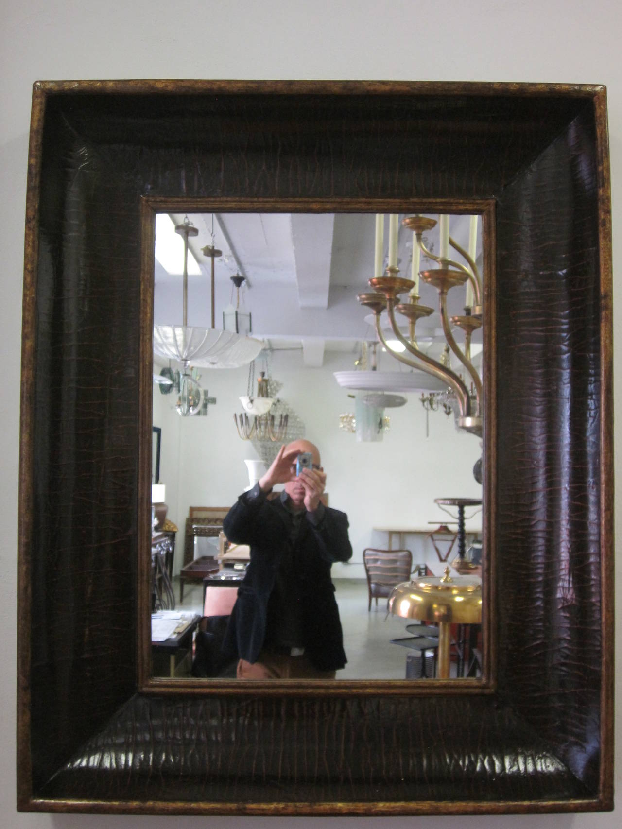 Stunning Italian Mid-Century Mirror in a Dramatic Concave Form with delicately painted and glazed frame revealing highlights of dark brown, ebony and red with gilt borders. The borders of the frame are a stunning 9