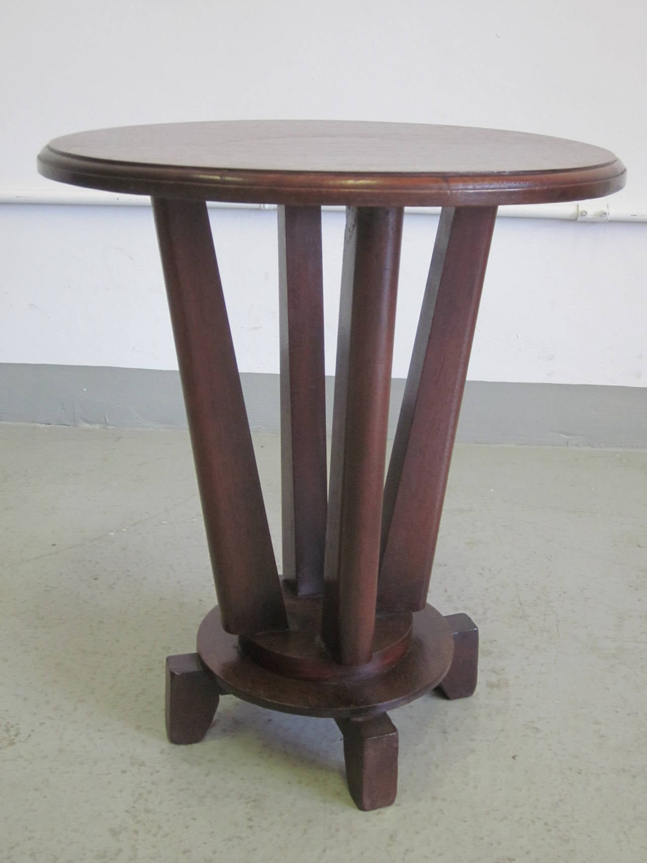 An elegant French Colonial gueridon, coffee table or side table composed of four sculpted feet supporting a central round base from which four sabered legs emanate and support a round top with inset apron.