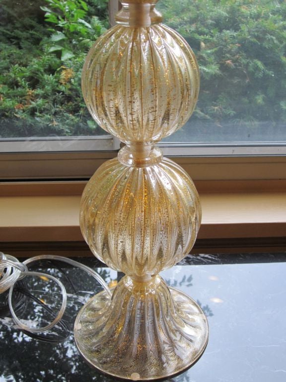 Pair of Italian Mid-Century style Murano glass table lamps attributed to Barovier e Toso in the form of stacked balls with clear glass with gold flecks interspersed.

UL wired for 2 lights at 100 watts each. Shades are hardback fabric. 