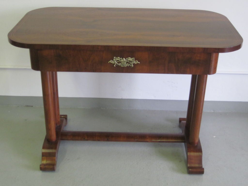 This desk / console with a simple, pure, modern design influenced French Art Deco in stunning matched walnut veneers and solid walnut. The piece features double columns legs on each side terminating in a scrolled base and united by a sober