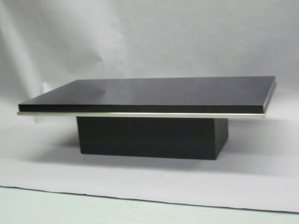 A Subtle, Elegant Italian Mid-Century Modern / Minimalist coffee table Attributed to Willy Rizzo in black lacquer with a satin nickel highlighted border resting a black composite base.

