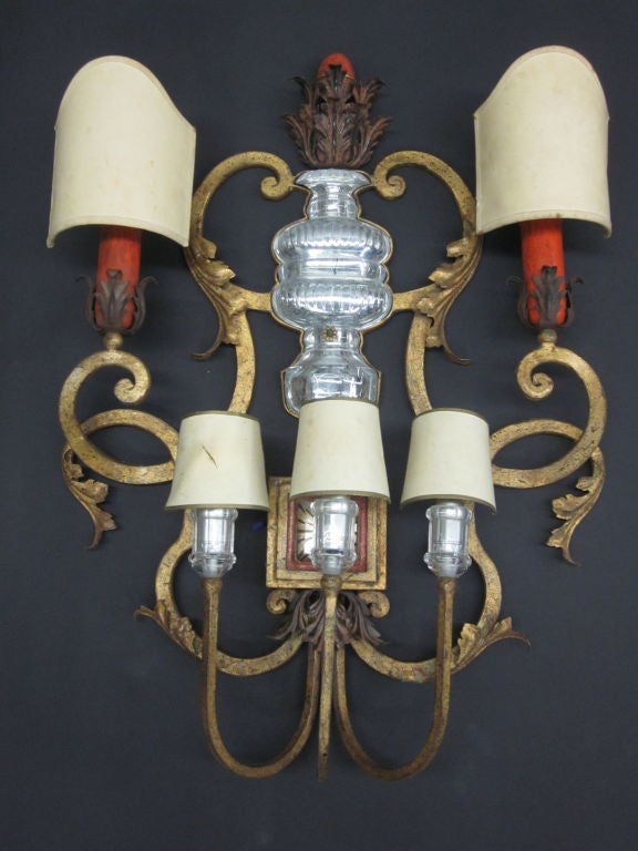 A Rare and Iconic French Mid-Century Modern neoclassical 5-light wall sconce by Maison Baguès. 

This dramatic piece stands over 30 inches high and is created with water gilded, handwrought iron in the form of volutes and supports a central
