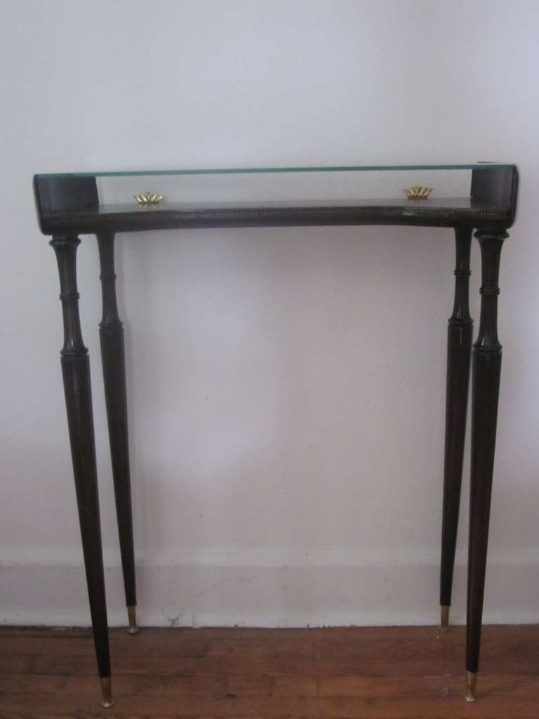 An elegant 'Piece Unique' Italian Mid-Century double level console table by Guglielmo Ulrich in the modern neoclassical (Late Art Deco) style featuring long dramatic legs ending in tapered sabots. The double level oval form wood and glass tops have
