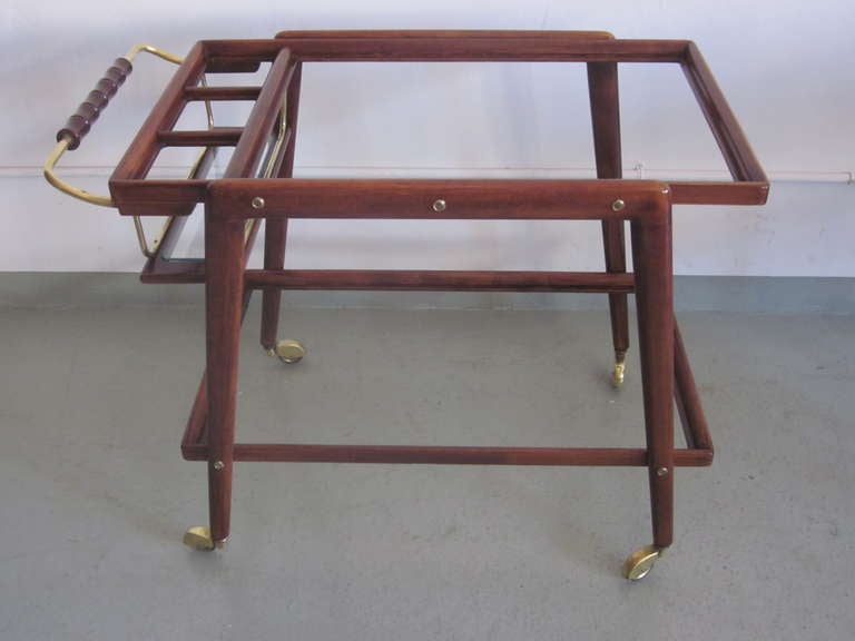 Elegant Italian Bar Cart / Serving Table in Walnut with Solid Brass Detailing with a Chic, Tapered Profile. The piece is sober, yet interesting to the eye and is practical with it's double level serving with an additional bottle rack integrated into