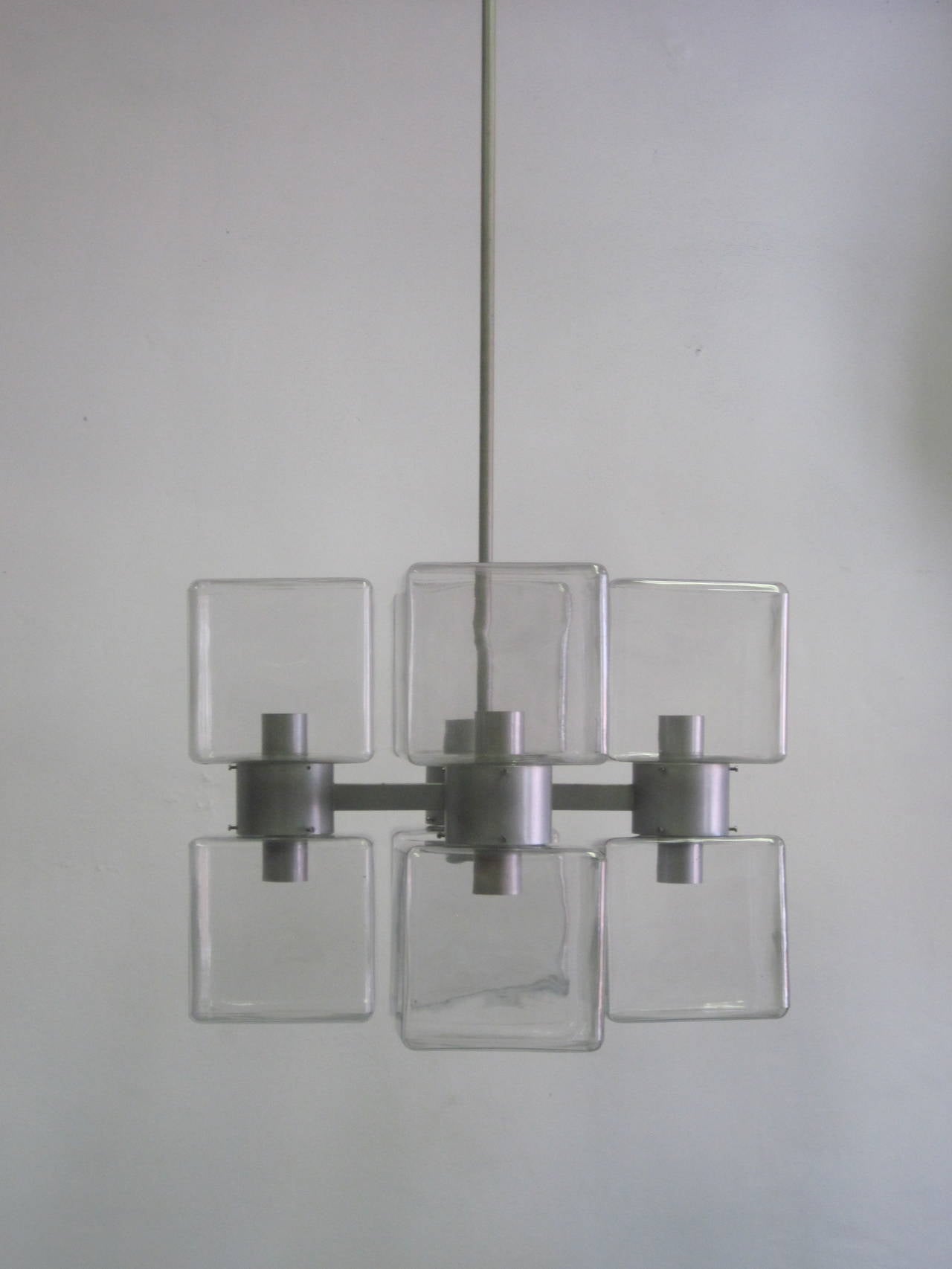 A Rare, elegant, sober, minimalist Italian Mid-Century Modern chandelier in the style of Fontana Arte composed of eight mold blown clear Murano glass reflectors arranged in a cross pattern. Each glass reflector has an Edison based socket and clear