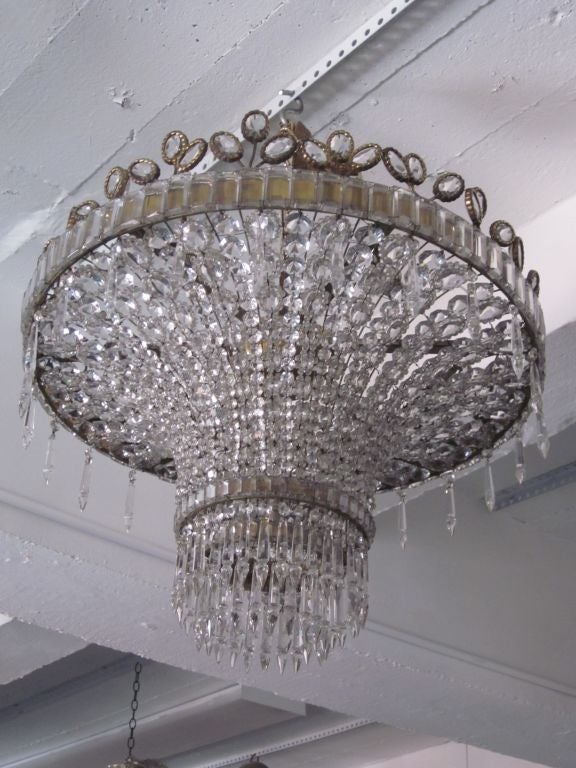 Elegant French Crystal Chandelier in the Modern Neoclassical Spirit by Bagues Arranged in a Pure, Sober Pattern and Trimmed with Abstract Crystal Flowers along the top border which Convey a Delightful Charm.