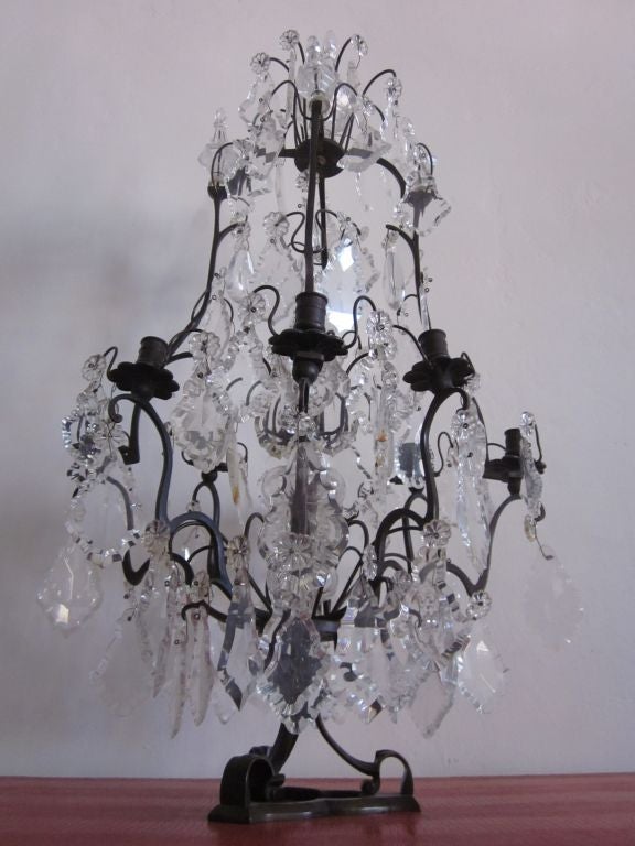 A rare French Modern Neoclassical table lamp / chandelier in crystal with a bronzed wrought iron frame with 8 arms. 

Can be used with candles or be electrified.