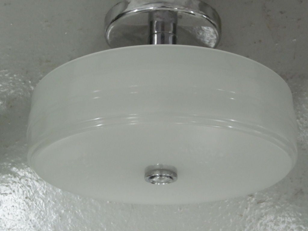 A modern, sober milk glass flush mount fixture with a nickeled metal armature and finial. Height from ceiling can be adjusted according to need.