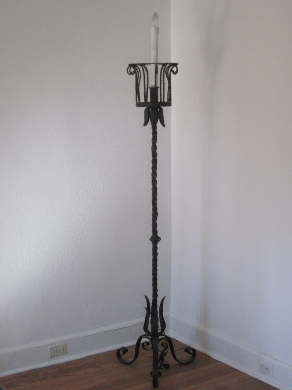 Elegante coppia di torchiere in ferro battuto a mano in stile Gilbert Poillerat del 1930-40 circa. Le lampade da terra sono caratterizzate da una base a treppiede, uno stelo in ferro battuto a mano e paralumi in ferro lavorati a mano, progettati in