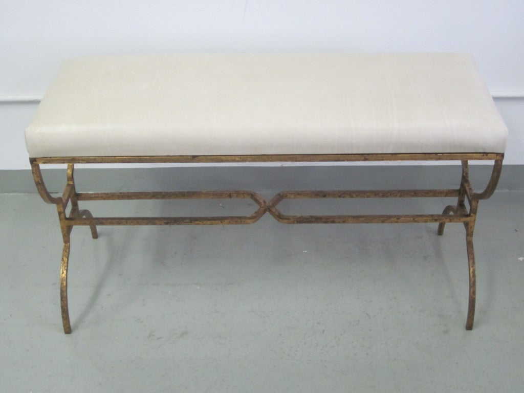 1 Large, Elegant Gilt Iron Bench by Maison Ramsay with Ivory Colored Leather Seat. The Wrought Iron Frame is Designed in a Stunnng Manner with X-frame Stretchers Uniting Curile Form Legs.