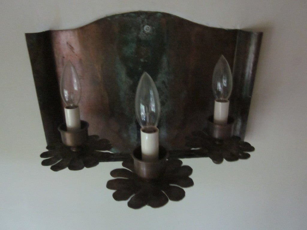 Rare pair of french 1940s-1950s sconces handcrafted in patinated copper with three lights emanating from simplified, floral bobeches. An exquisite blend of sobriety and quiet drama gives these pieces a timeless quality.

Literature: See similar