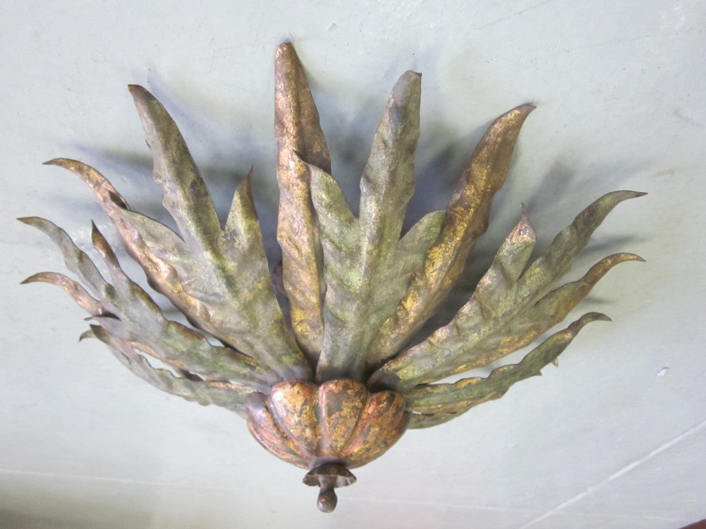 French sunburst/starburst flush mount fixture in patinated and gilt iron utilizing acanthus leaves to create the sun/star pattern.

Can be flush mounted or suspended via stem to conform to your specifications.