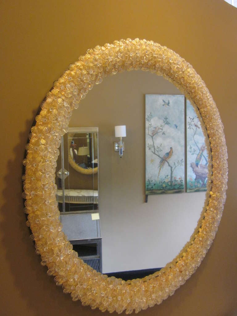 Two elegant Italian Mid-Century style Murano glass mirrors attributed to Seguso in a circular form and lined with subtle handblown Murano glass flowers in a clear and gold tones. 

There are two pairs. The larger pair is 36.25 in diameter and the