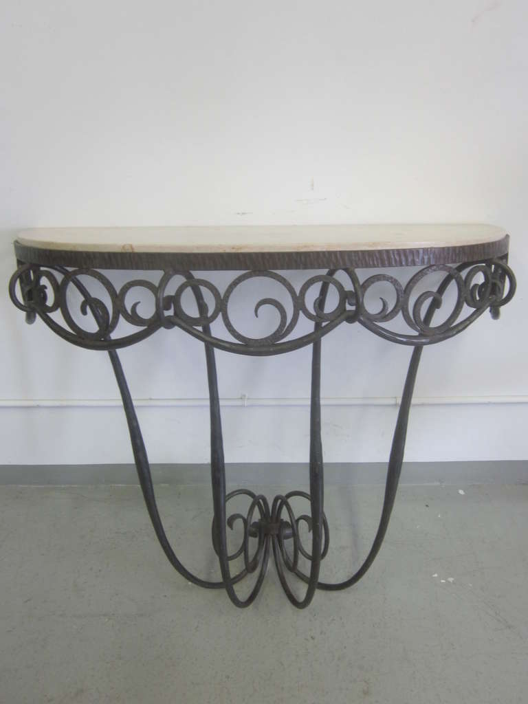 An Elegant and Timeless French Art Deco Console by Edgar Brandt in hand hammered wrought iron with an inset top of French Jura Limestone. This important piece is characteristic of Brandt and the French Art Deco period with its organic, rhythmic,