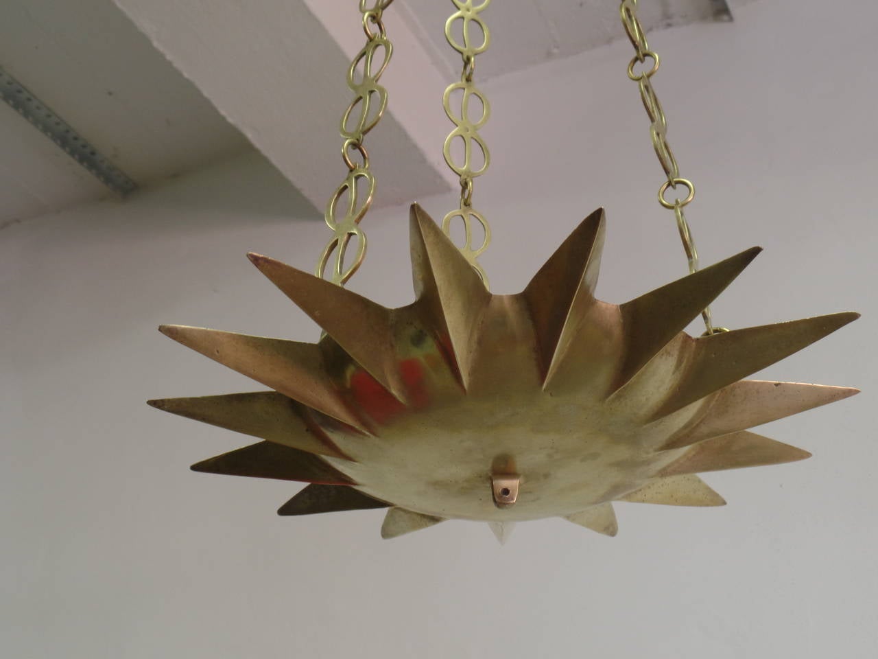 Stunning early 20th century French solid brass / gilt bronze 16 point star / sunburst form chandelier with delicate handmade chain in the modern neoclassical taste. The quality of design and materials are of the highest quality and the piece can be