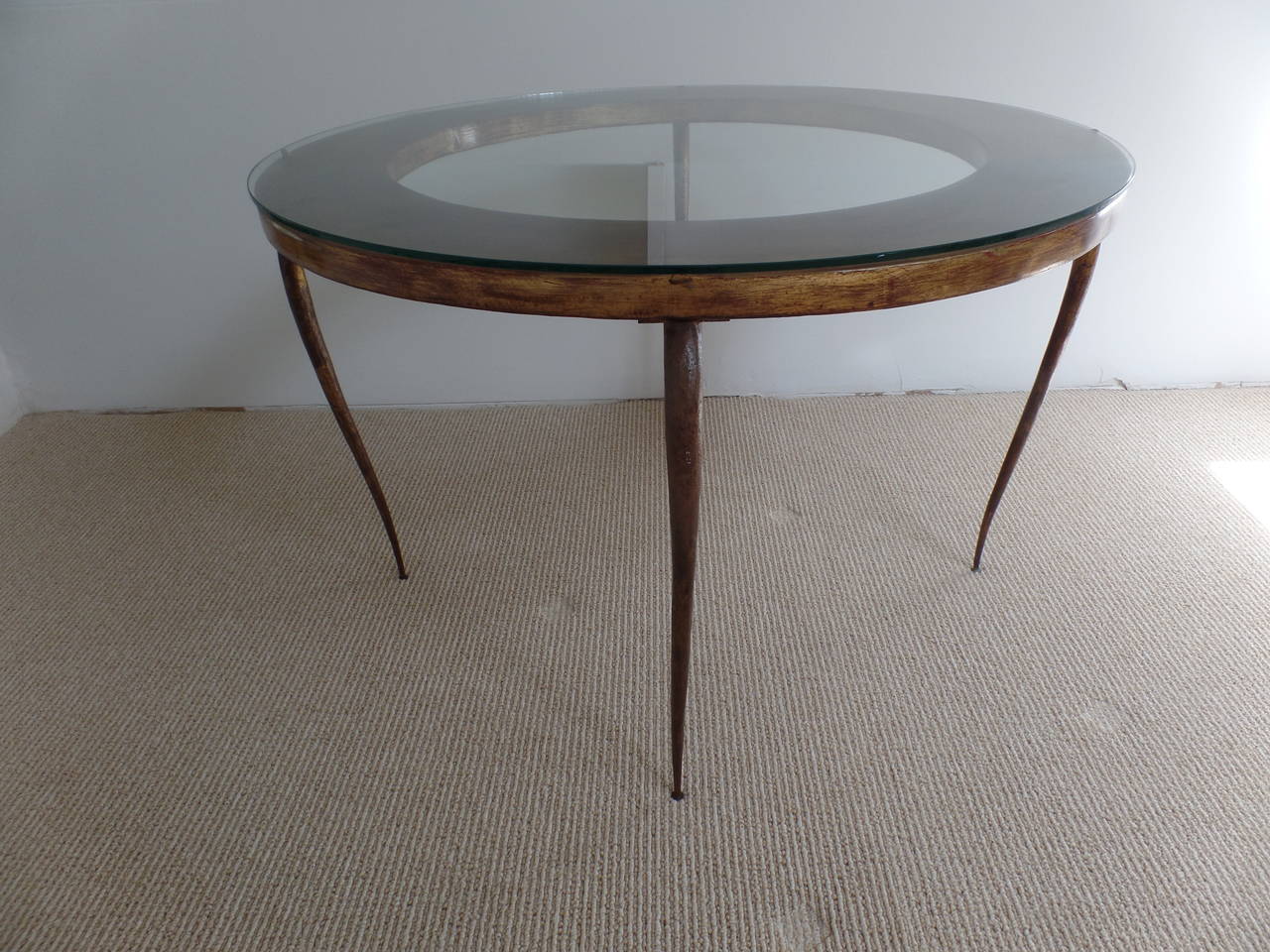 An elegant and timeless round French Mid-Century Modern Neoclassical cocktail table by Rene Prou with stunning, delicately hand-hammered tapering legs. The legs and frame are delicately gilt with the worn patina of the legs adding to the subtle